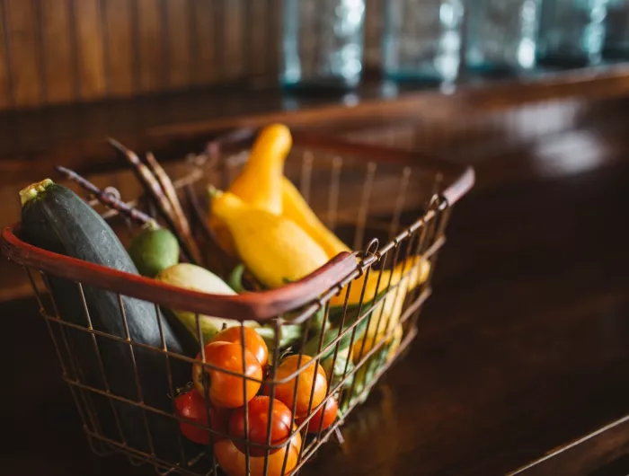 A shopping basket full of squash and tomatoes