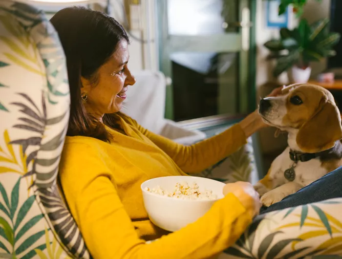 a woman eating popcorn while petting her dog