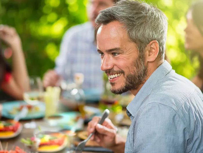 man smiling while eating with a group of people