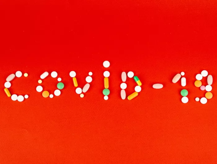 Various pills and capsules arranged to spell "Covid-19"