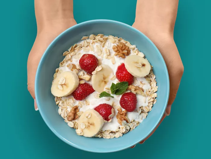 blue bowl of oatmeal with berries and bananas.