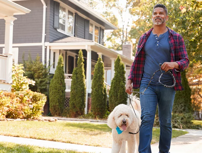 man walking dog on sidewalk