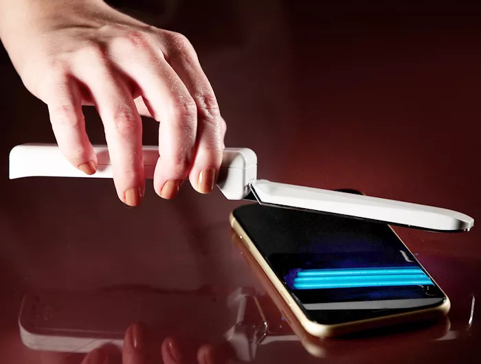 person using UV wand over cell phone