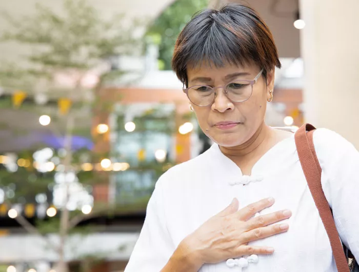 woman standing and holding her chest