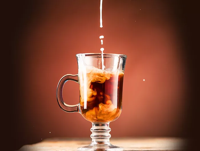 mug of coffee with creamer being poured in
