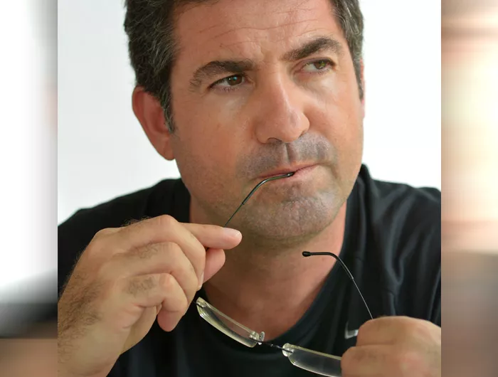 Man bighting glasses arm and thinking