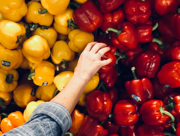 A woman selecting a red bell pepper