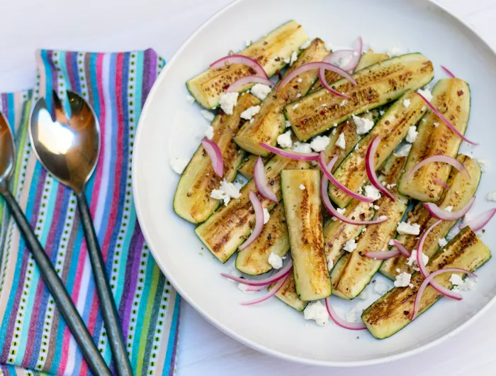 plate filled with greek zucchini slices with a colorful napkin and utensils