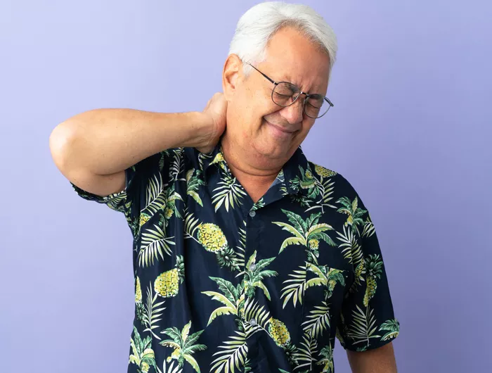 Older man holding the back of his neck and wincing