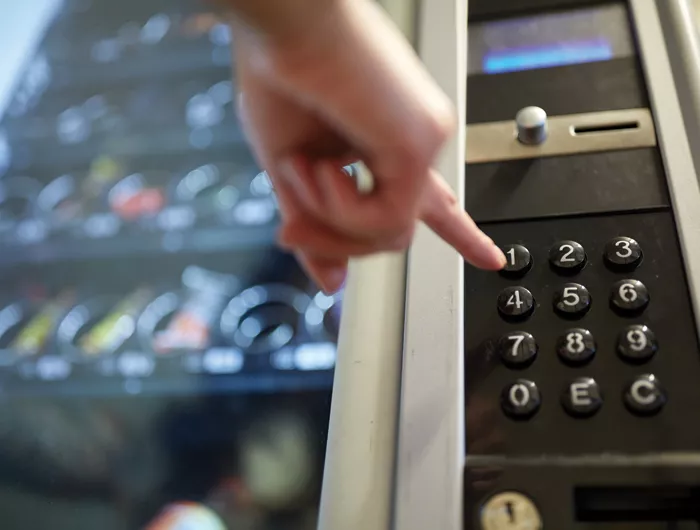 A hand making a choice at a vending machine