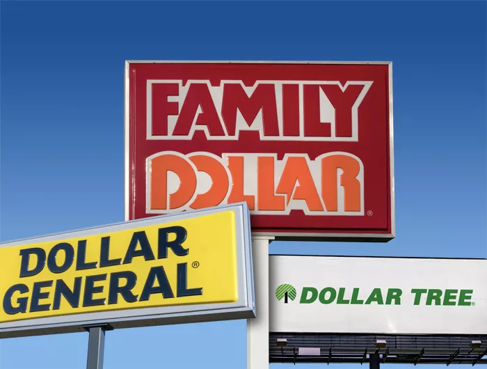 Signs for Dollar General, Family Dollar, and Dollar Tree with a blue sky in the background