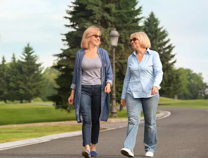 two women walking on a tree lined street