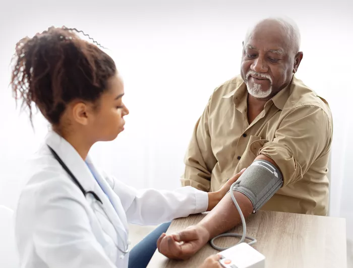 doctor checking blood pressure of older man