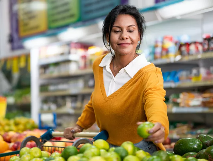 woman picking up a green apple in a grocery store