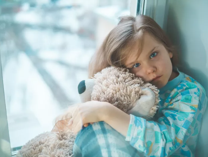 Hospitalized child hugging a teddy bear