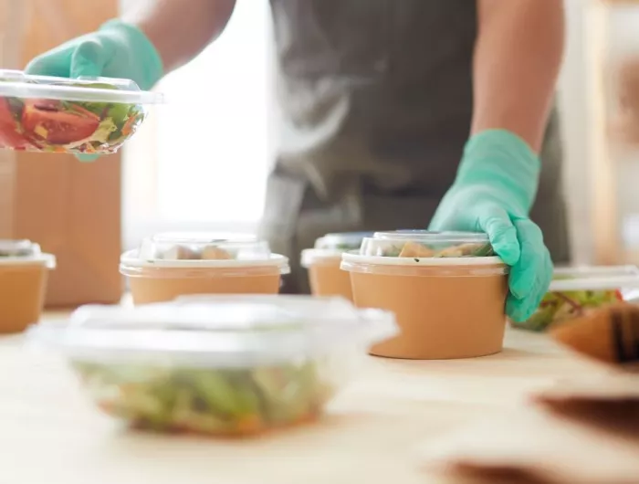 Close up of worker wearing protective gloves while packaging food