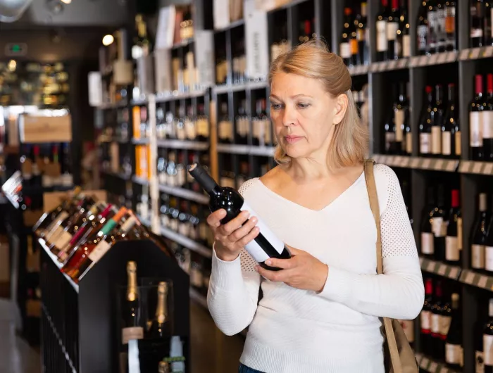 A woman checking the label on a bottle of wine