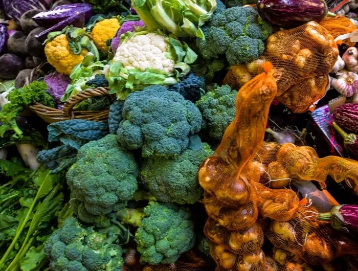 Seasonal produce at a market in October, including broccoli, eggplant, garlic, cauliflower