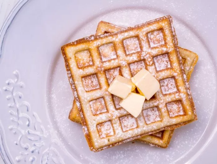 Prepared frozen waffles; flat lay on a white ceramic plate with butter