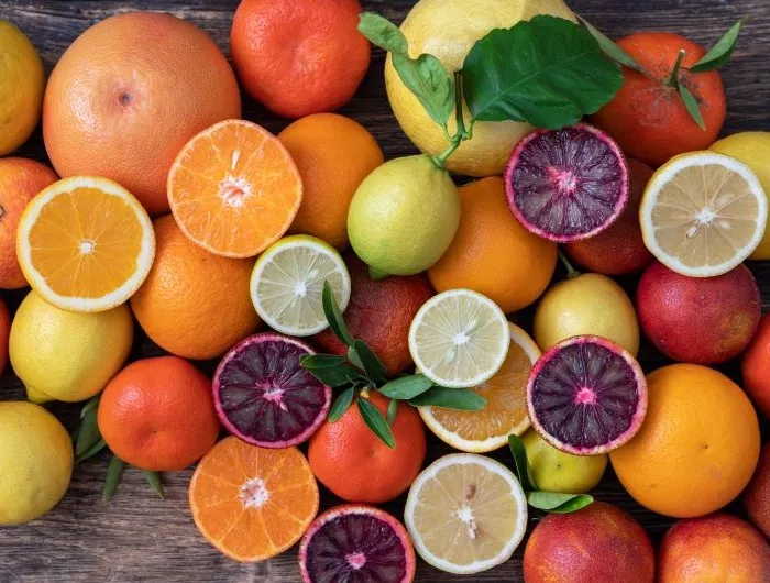 Assorted seasonal citrus fruit, including oranges, tangerines, grapefruit, limes and lemons, on a wooden table