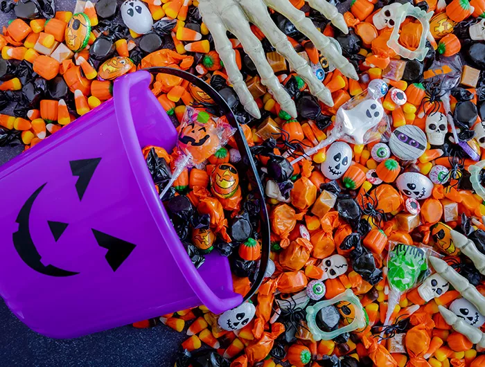 Halloween candy spilling out of purple pumpkin bucket