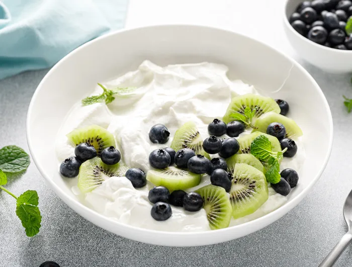 bowl of yogurt with blue berries and kiwis