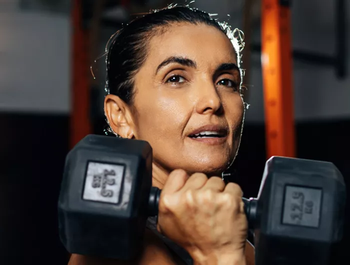woman holding a dumbbell under her chin 