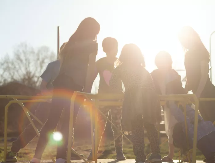 A group of kids on a merry-go-round in a park.