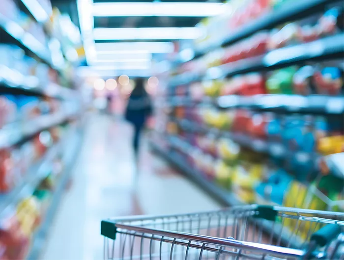 grocery cart in focus in the foreground with grocery store shelves out of focus in the background