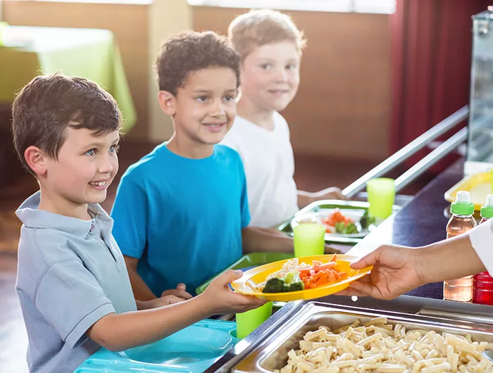 Woman serving food to schoolchildren