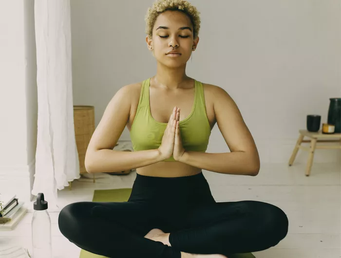 woman sitting crisscross with prayer hands as a yoga pose