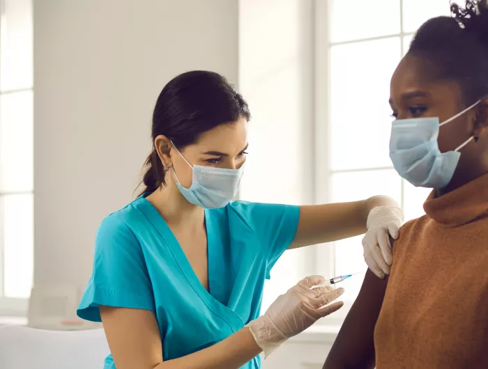 a doctor giving a woman a vaccination shot