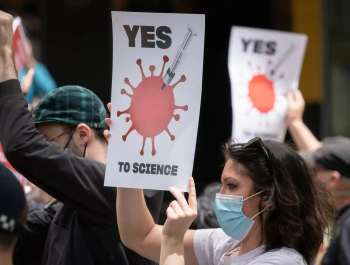 A group of people holding pro-science signs and wearing masks