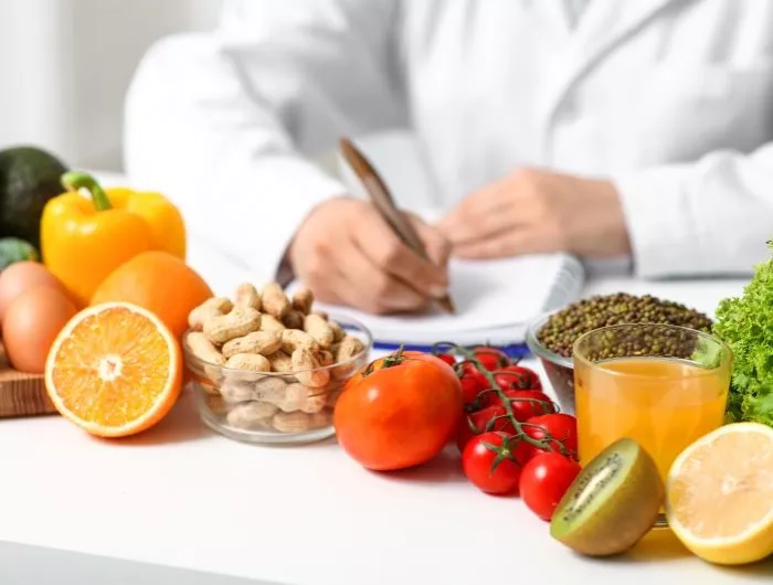 Young female nutritionist with healthy food writing diet plan in office, closeup