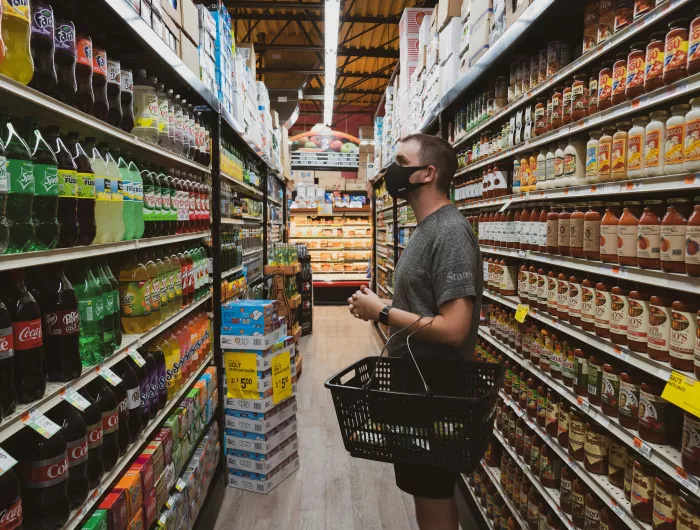 A man with a shopping basket eyeing the soda display in a supermarket