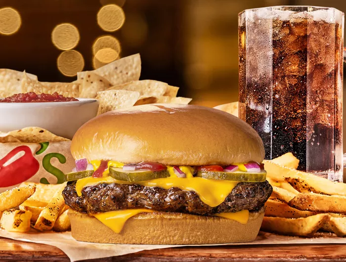 Chilis Big QP burger surrounded by fries with chips and salsa and large soda