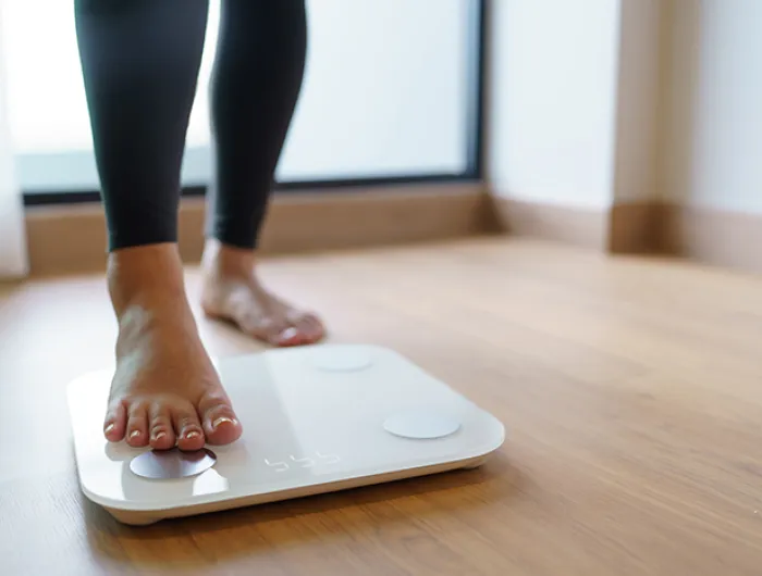 person stepping on a scale on wood floor