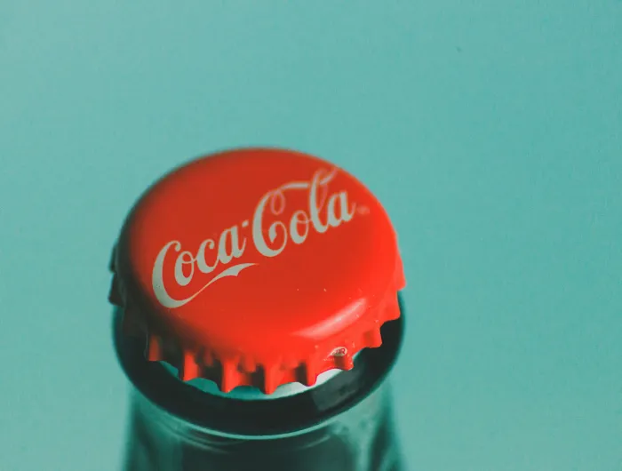 A red Coca-Cola bottle cap against a sky blue background