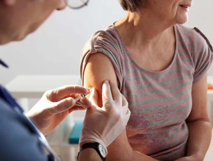 An older woman receives a vaccination shot in a doctor's office