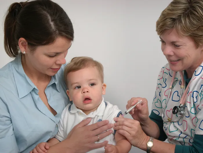 A pediatrician giving a shot to a baby.