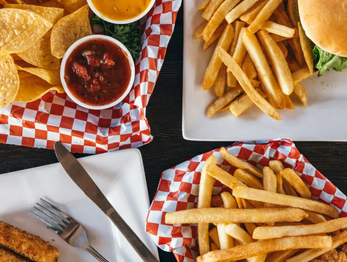 A collection of salty foods: tortilla chips, fries, a burger, and mozzarella sticks
