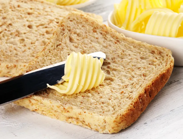 knife spreading butter on slice of bread