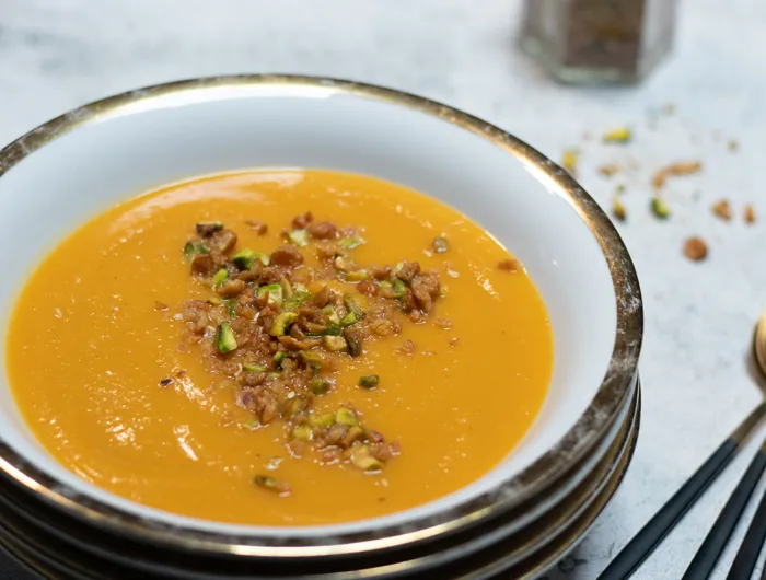 white bowl filled with butter nut soup and dukkah