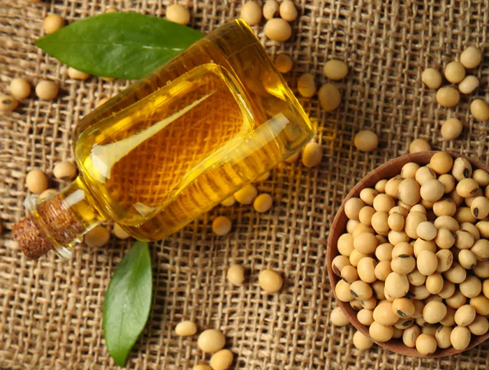 glass bottle full of seed oil on burlap background with seeds sprinkled around