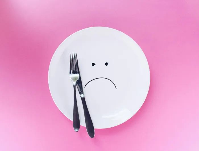 An empty plate with a sad face drawn on with marker.