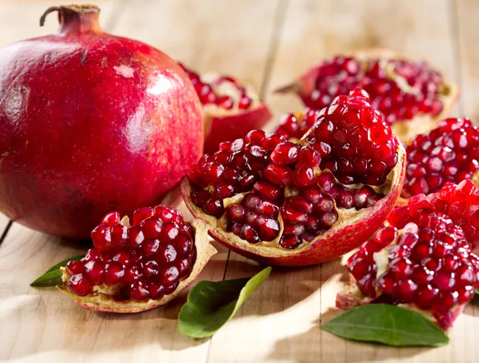 1 whole pomegranate and one split up laying next to each other 
