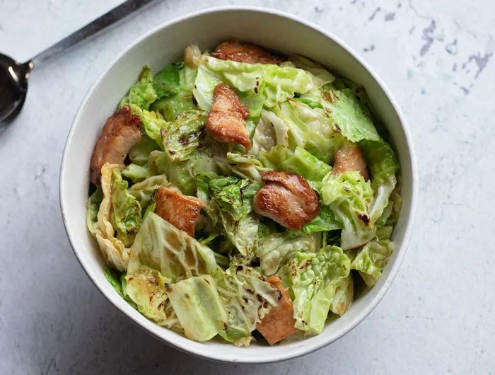 bowl filled with green cabbage and chicken stir fry on white counter