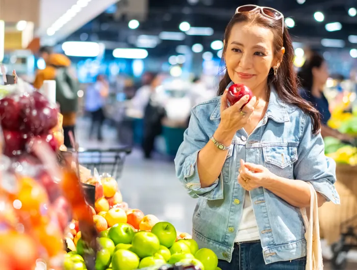 woman at grocery store holding a apple in the produce section