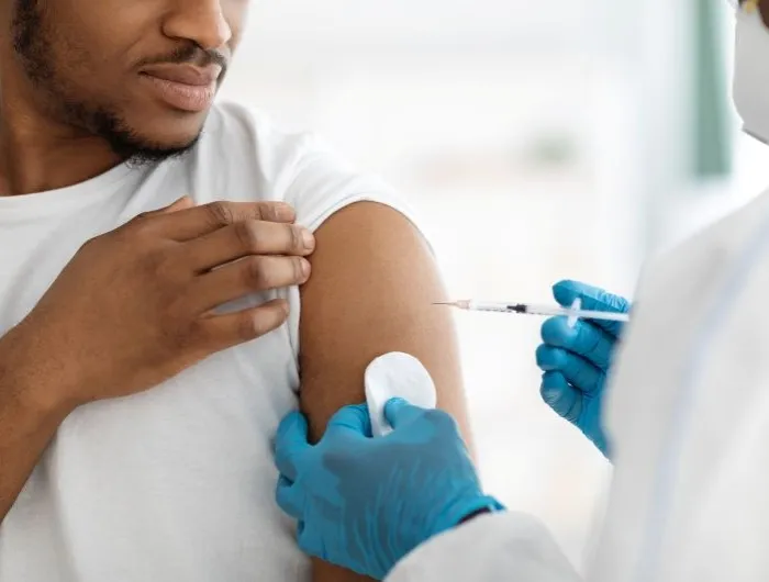 A medical professional administers a Covid vaccine to a Black man