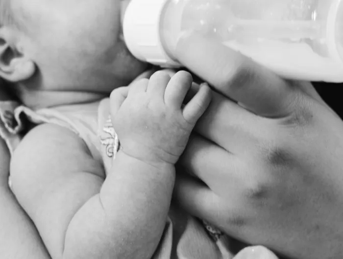 An infant drinking from a bottle in black and white